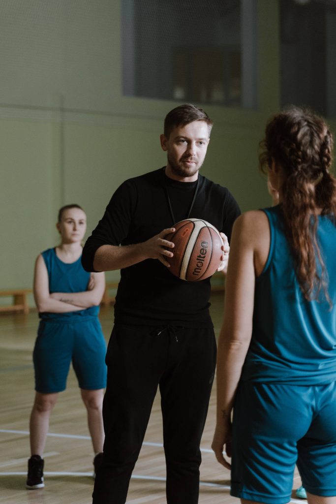Basketball coach instructing female players in gym with Molten ball during training session wallpaper