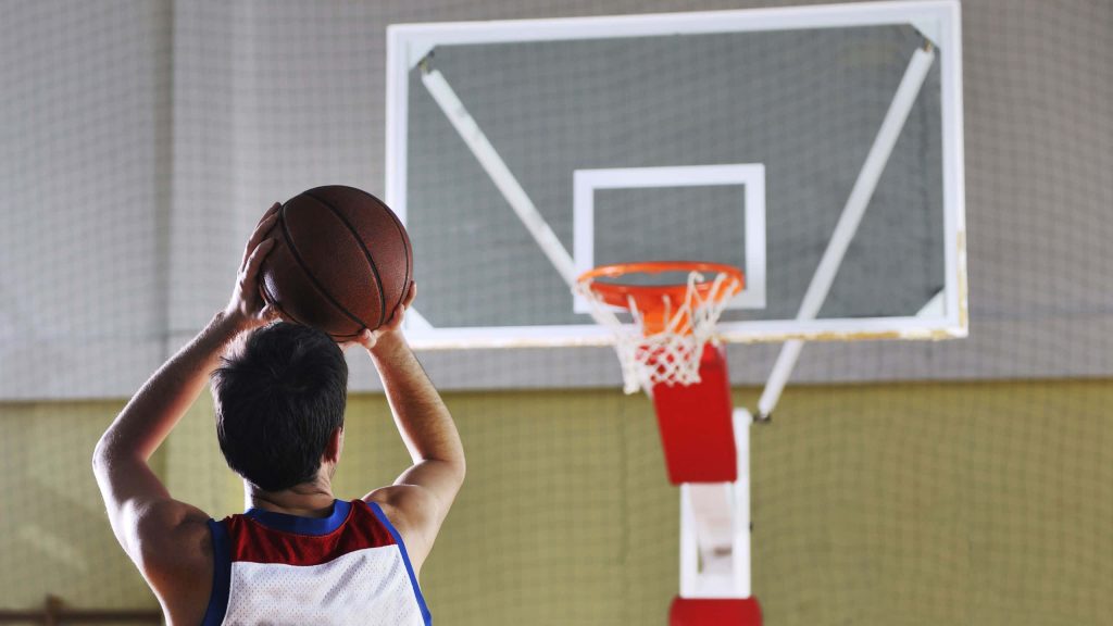 Focused basketball player in white red blue jersey aiming for hoop indoor gym action wallpaper