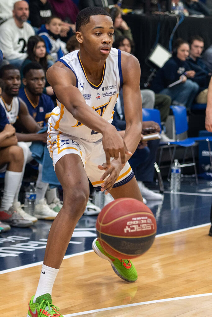Basketball player skillfully passing ball during intense game with spectators on court background Wallpaper