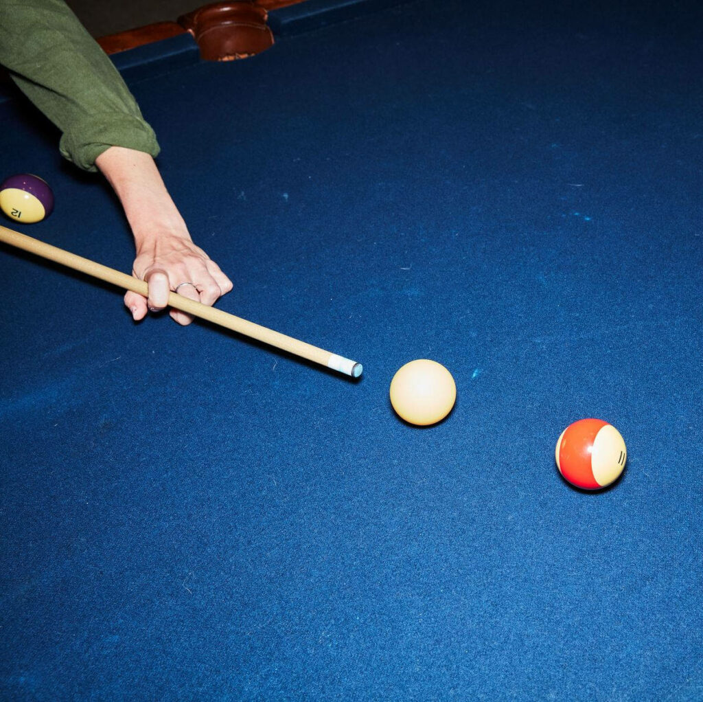 Billiards player aiming cue ball on blue pool table targeting colored ball precise shot wallpaper