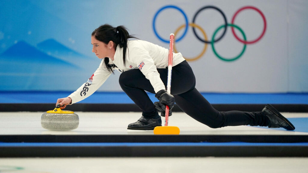 Focused Female Curler in Action with Olympic Rings - Stunning Wallpaper