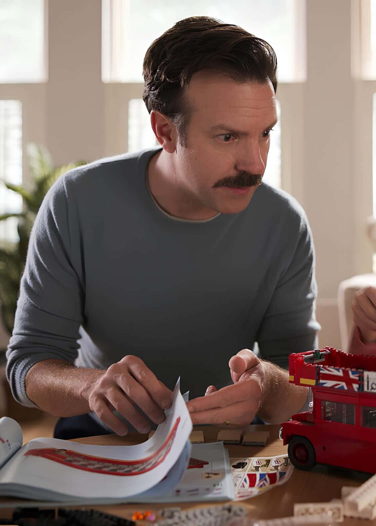 Focused Man Assembles Toy Bus in Relaxing Well-Lit Room Wallpaper