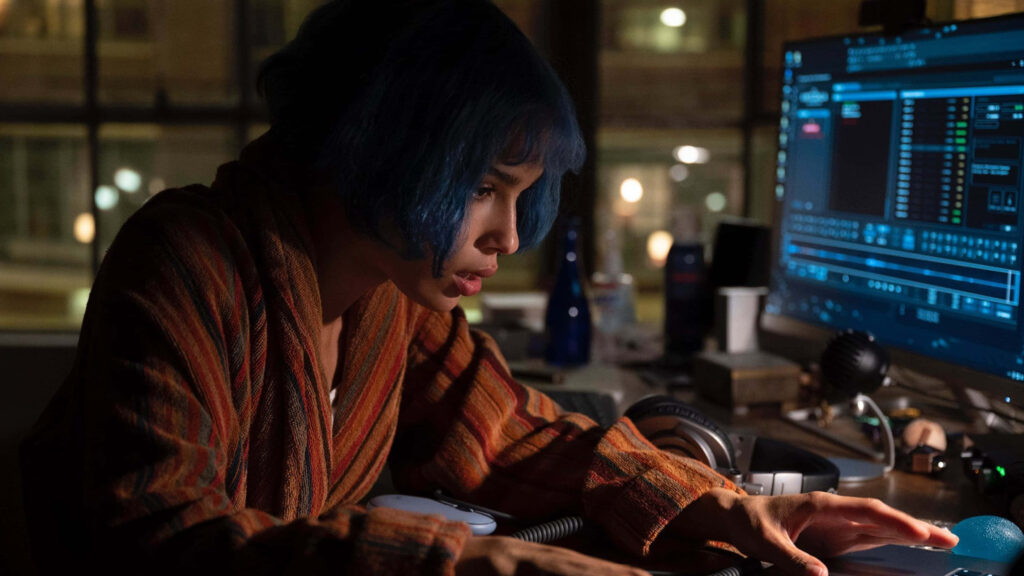 Focused woman with blue hair working late at night illuminated by computer screen glow wallpaper