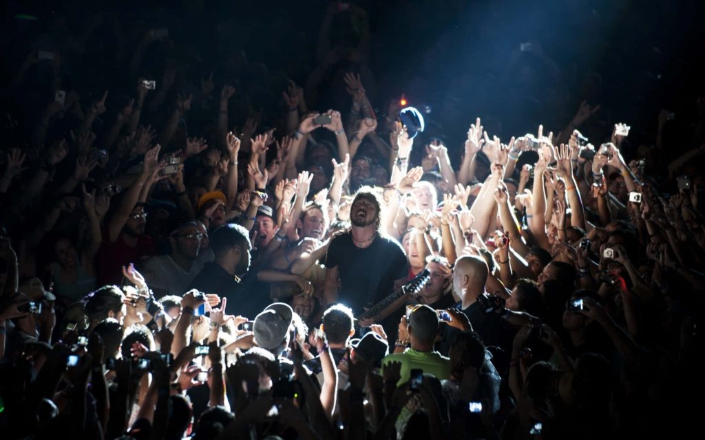 Dave Grohl singing live at Foo Fighters concert with energetic crowd and vibrant stage lights Wallpaper