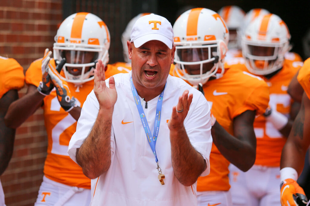 Football coach energizing team in orange and white uniforms before the game on wallpaper background