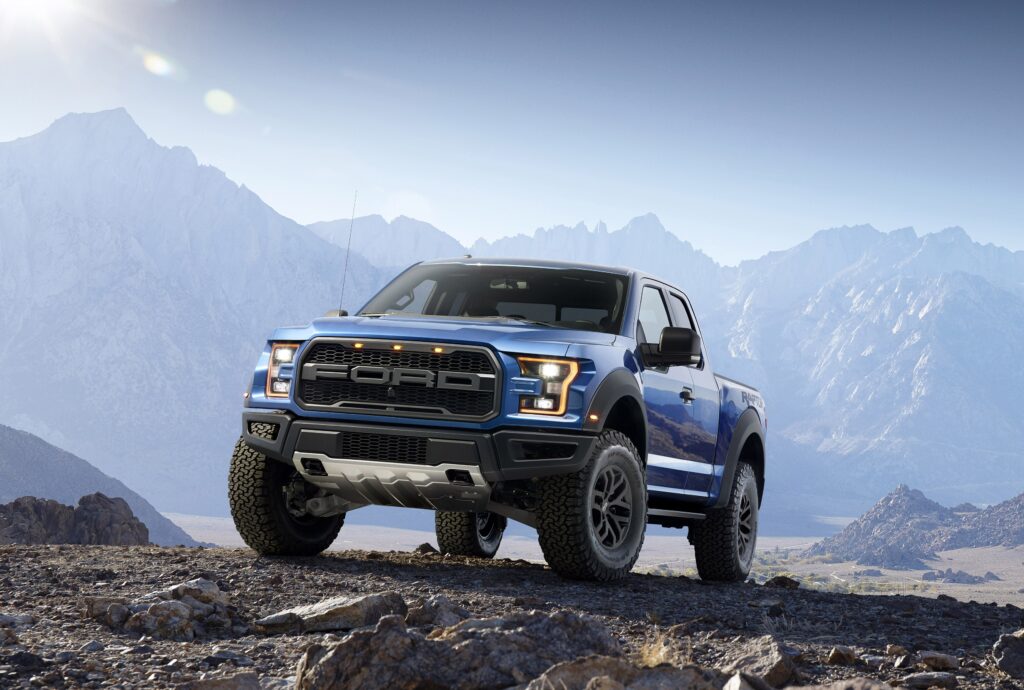 Ford F-150 Raptor: Rugged Blue Pickup Over Rocky Terrain Background Wallpaper