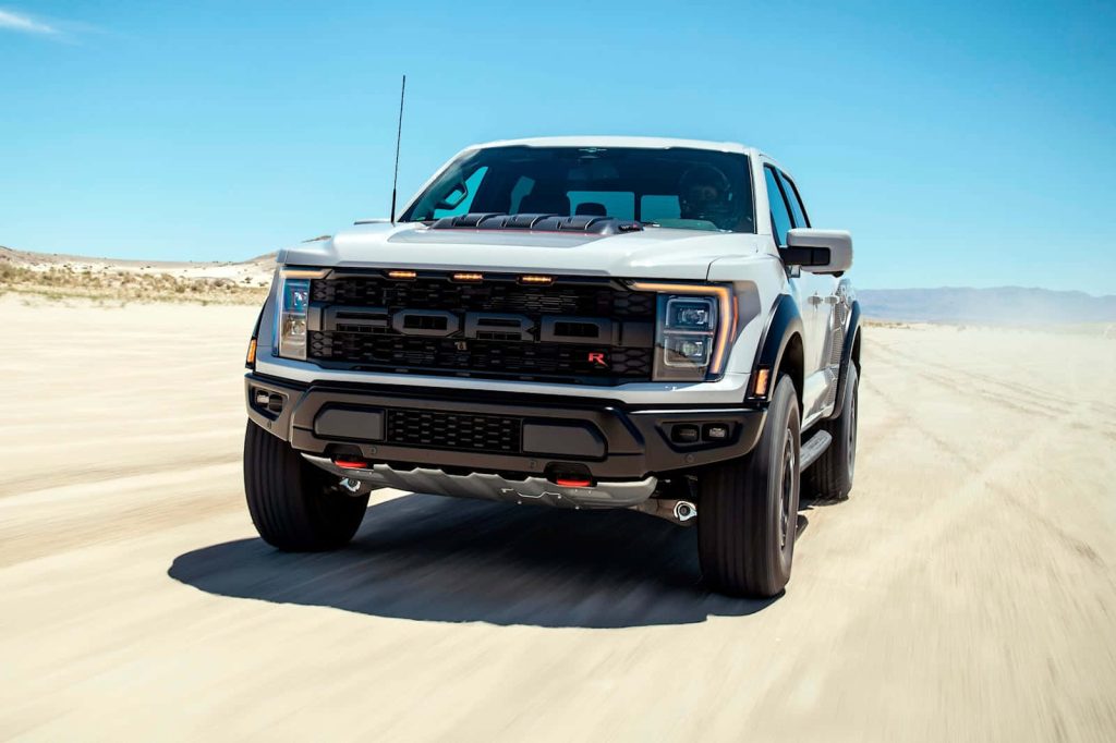 White Ford F-150 Raptor R speeding across desert showcasing rugged grille and off-road power Wallpaper