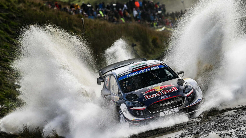 Ford Fiesta rally car speeding through water splash showcasing power and agility in motorsport Wallpaper