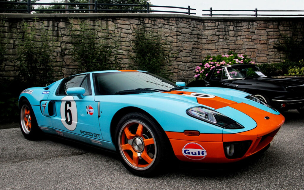 Ford GT in iconic light blue and orange Gulf livery with racing stripes parked outdoors Wallpaper