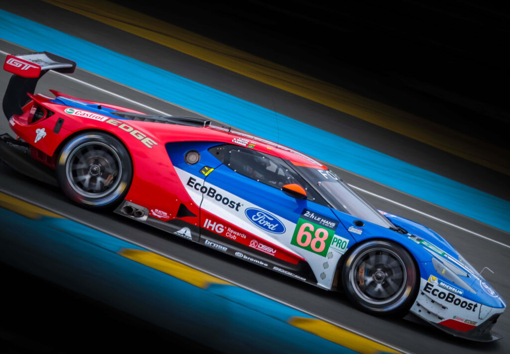 Ford GT race car number 68 speeding on track with vibrant red blue white livery and sponsor logos Wallpaper