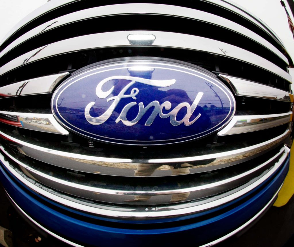 Close-up fish-eye view of Ford logo on shiny chrome grille with sharp metallic blue details Wallpaper