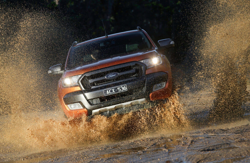 Ford Ranger Raptor driving through muddy water off-road showcasing rugged powerful design wallpaper