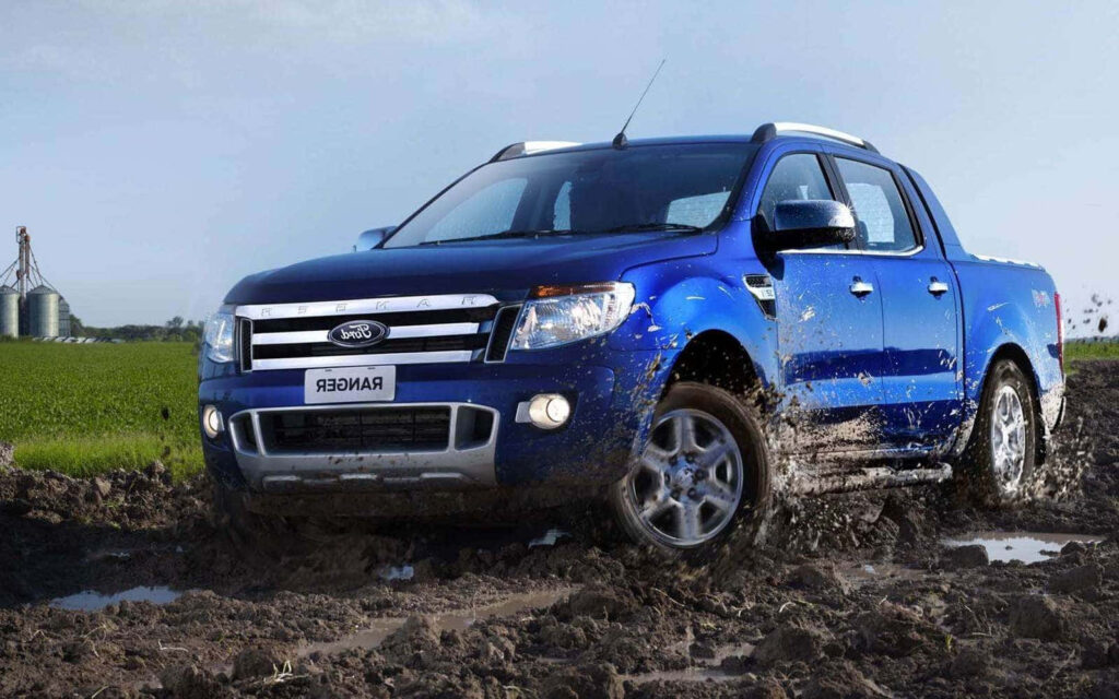 Blue Ford Ranger driving through muddy off-road trail showcasing rugged performance wallpaper