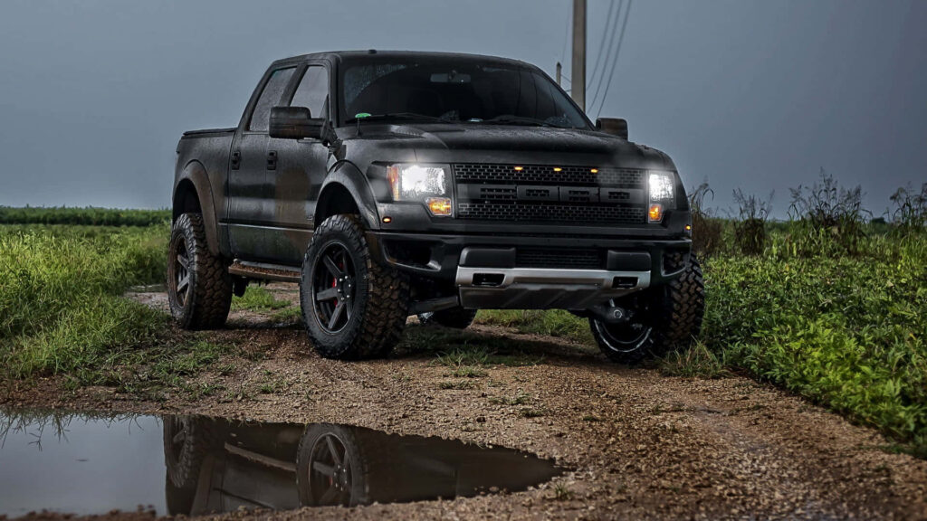 Rugged Ford truck on muddy path with bold headlights and tough off-road tires wallpaper