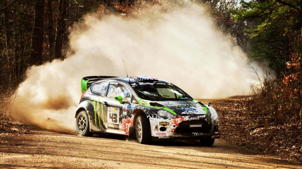 Fierce rally car kicking up dust on wooded track - dynamic background Wallpaper