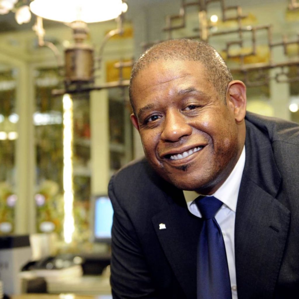 Forest Whitaker portrait in professional dark suit smiling warmly with blurred office background Wallpaper