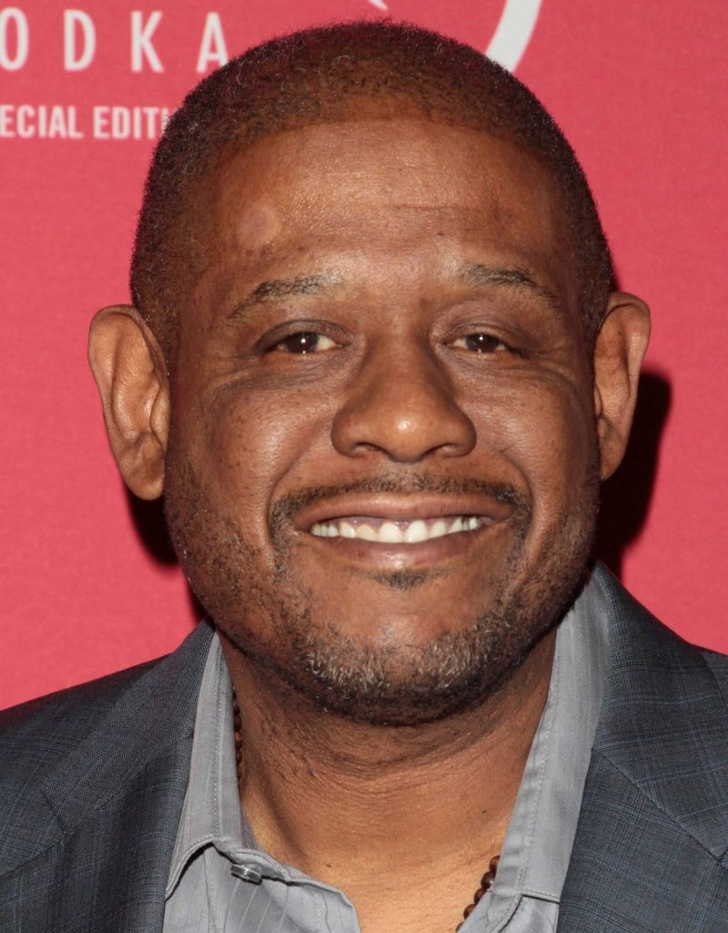 Forest Whitaker smiling in grey suit on red carpet with vodka special edition backdrop wallpaper