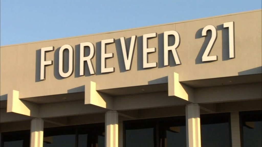 Forever 21 logo on beige building facade with sunlight and sharp shadows fashion background wallpaper