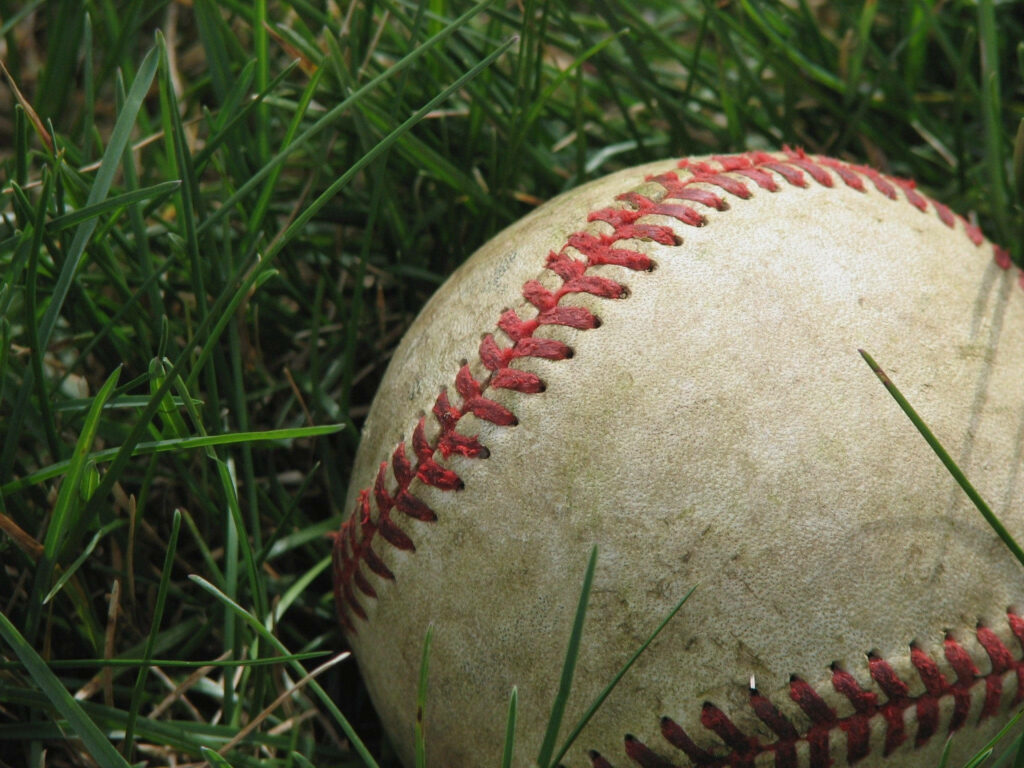 Forgotten and Grime: A Tale of a Used Baseball on the Grass Wallpaper