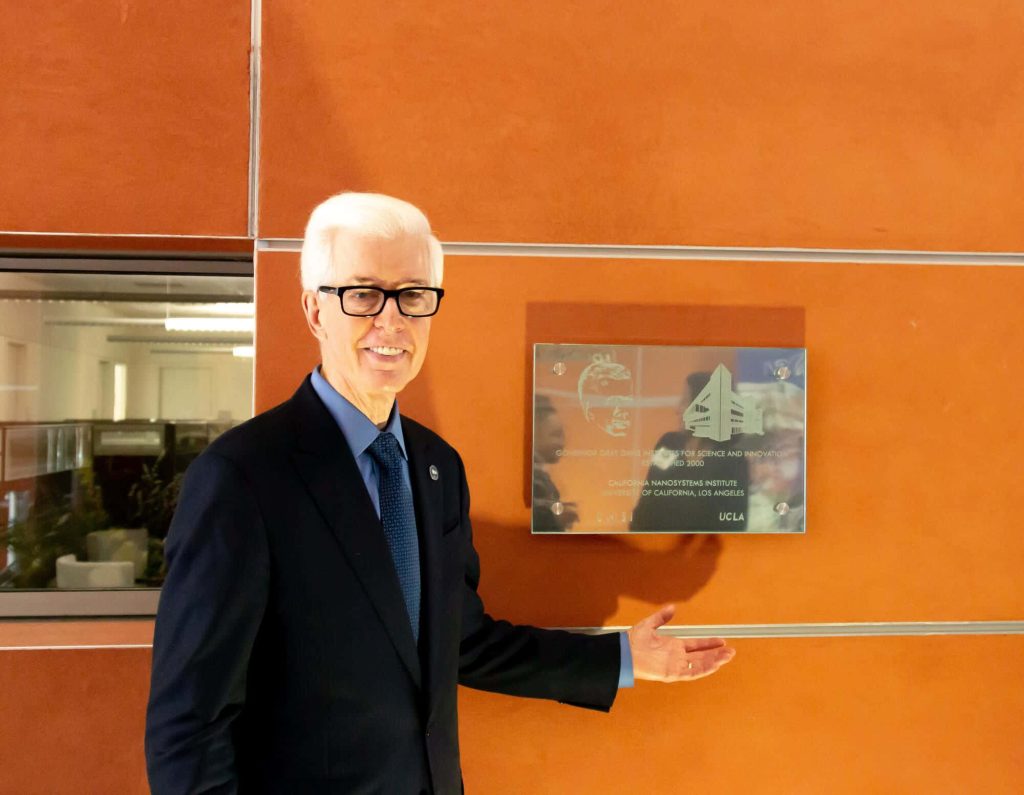 Former California Governor Gray Davis gestures to Institute plaque at UCLA NanoSystems vibrant wall Wallpaper