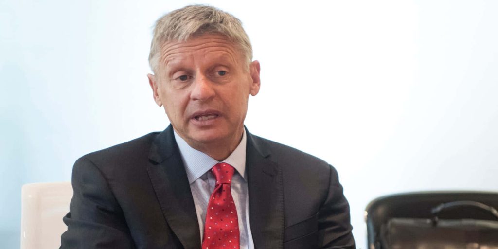 Former Governor Gary Johnson speaking in dark suit red polka-dot tie bright corporate background Wallpaper