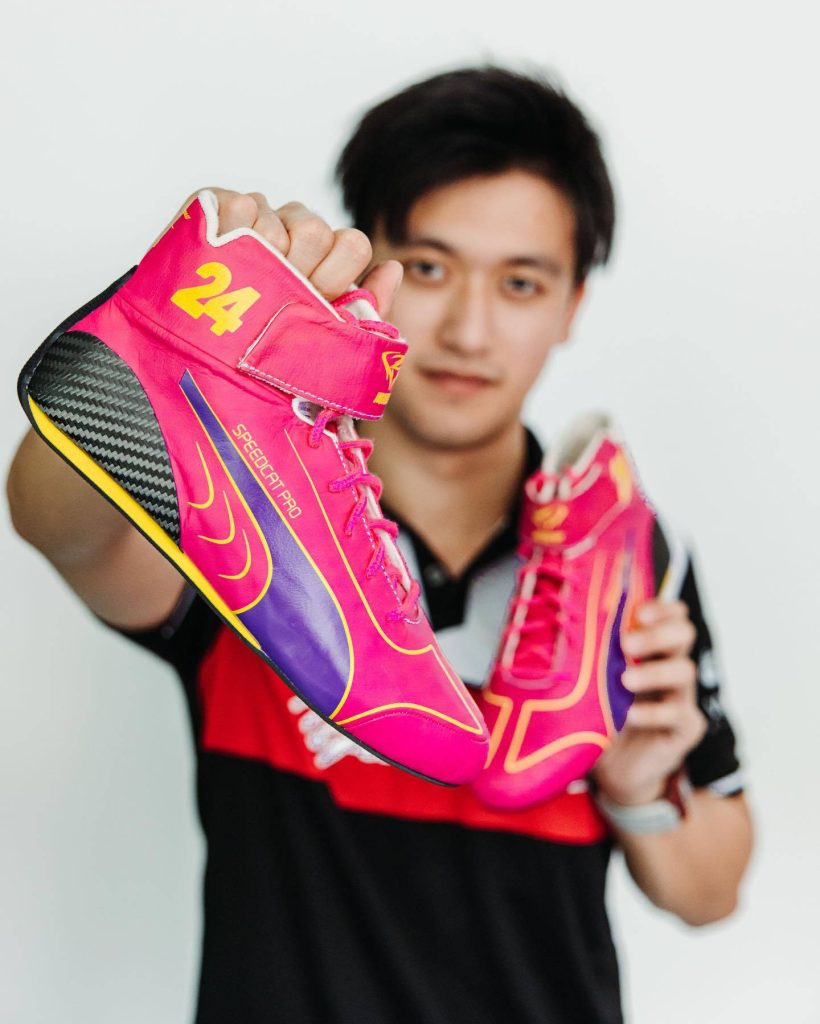 Formula 1 driver Zhou Guanyu shows custom pink Puma Speedcat Pro racing shoes number 24 vibrant portrait Wallpaper
