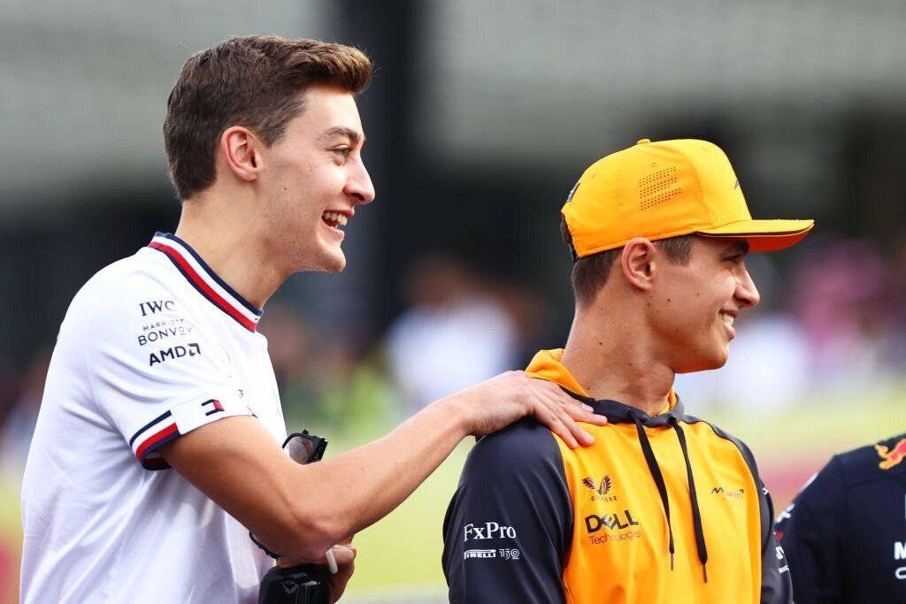 George Russell and Lando Norris in team gear share a friendly moment in bright natural light Wallpaper