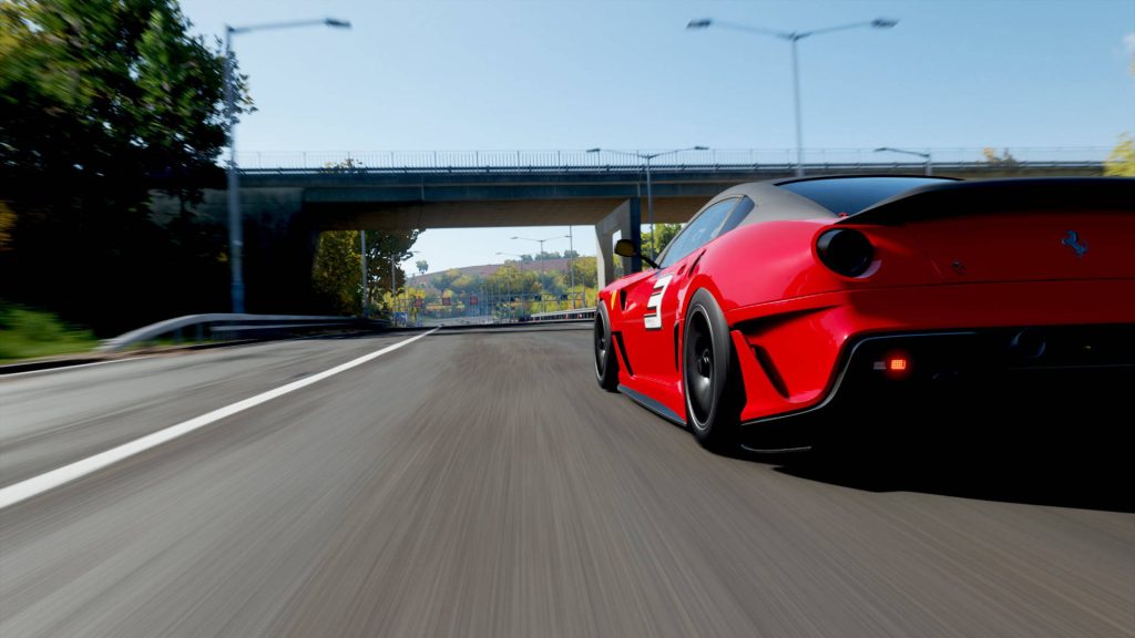 Red Ferrari 599XX Evo racing fast on sunlit highway Forza Horizon 4 dynamic CGI wallpaper