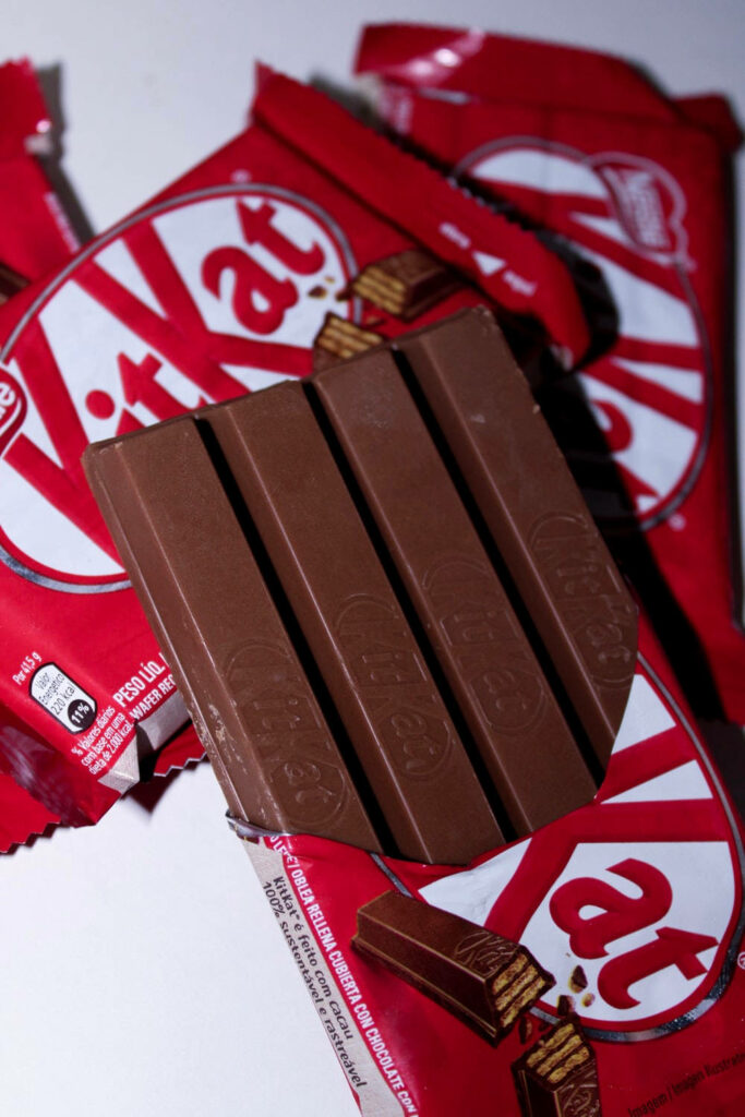 Delicious Four-Finger Kit Kat: Chocolate Bar on Red Wallpaper
