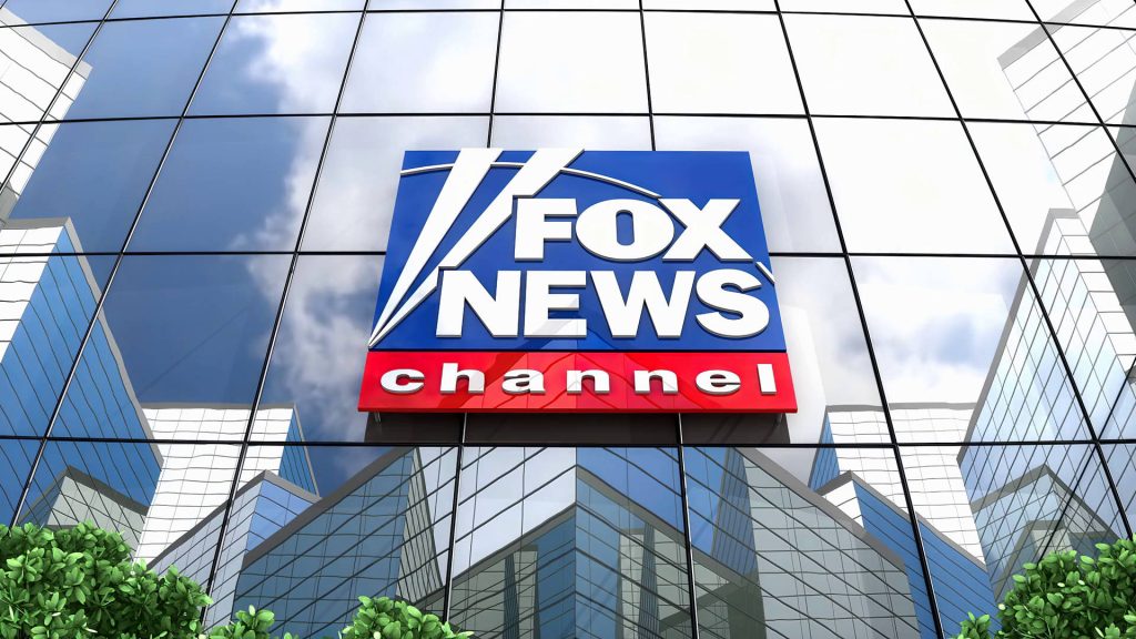 Fox News Channel logo on glass building facade with reflective windows and blue sky background Wallpaper