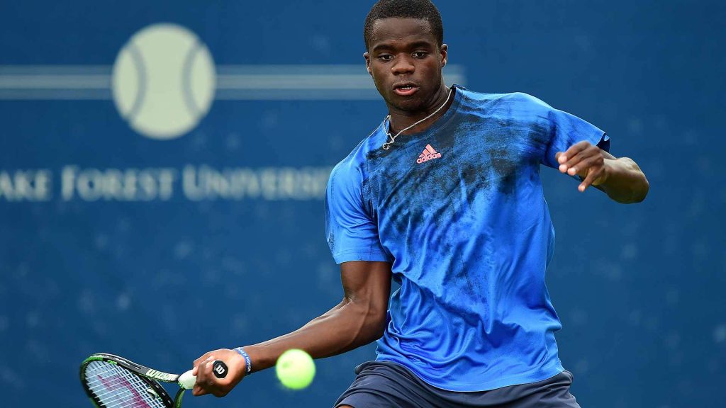 Frances Tiafoe powerful forehand tennis action in blue Adidas with Wilson racket vibrant wallpaper