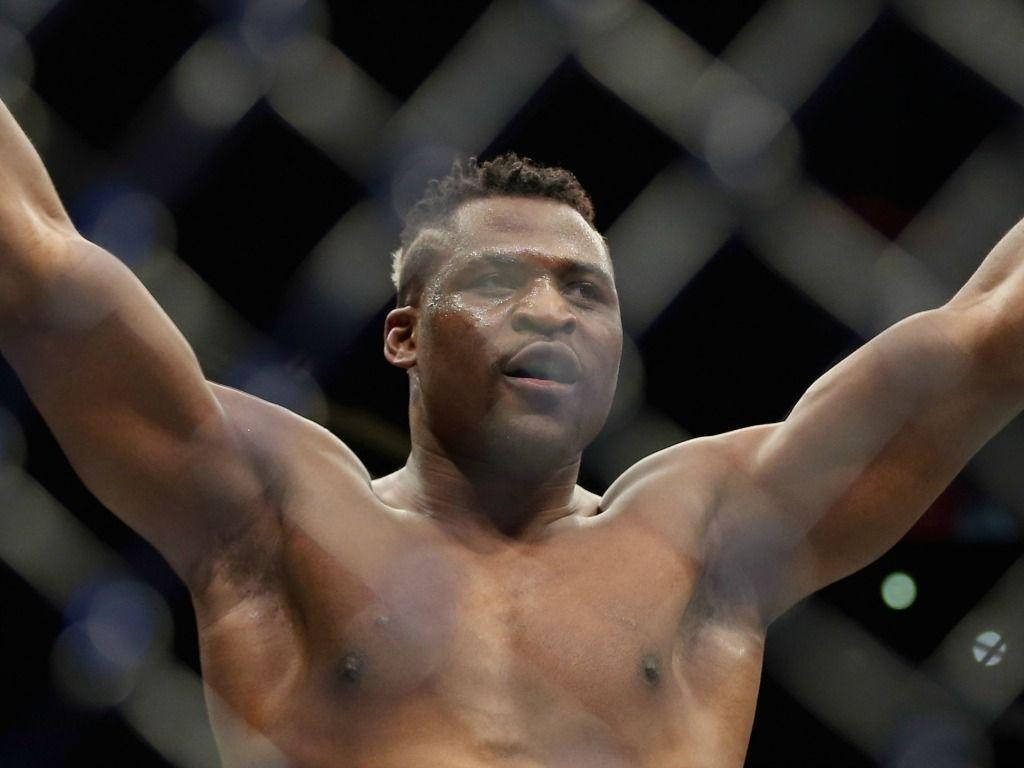 Francis Ngannou celebrating MMA victory inside octagon intense expression sweat shining Wallpaper