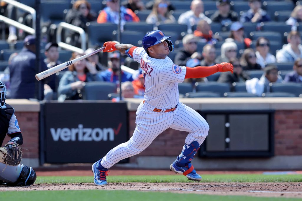 Francisco Alvarez swinging powerfully in blue orange Mets uniform during sunlit MLB game Wallpaper