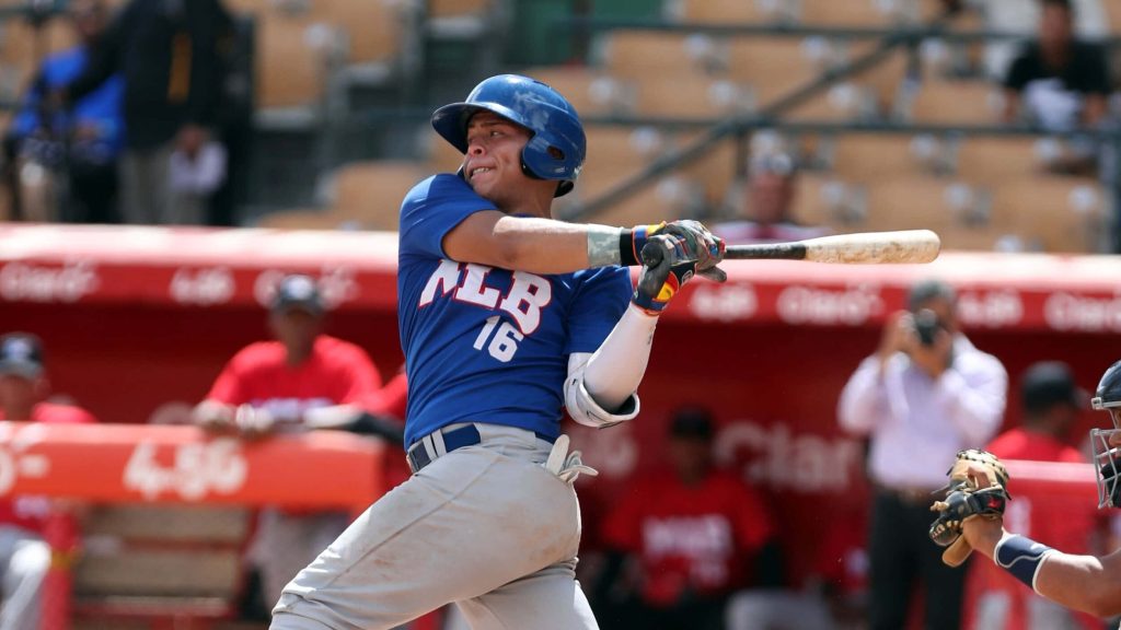 Francisco Alvarez swinging bat in blue Futures Game jersey at bright outdoor MLB stadium action shot Wallpaper