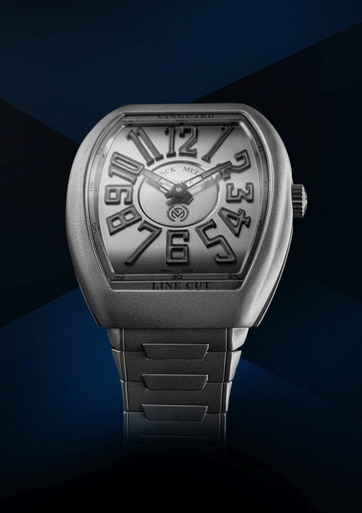 Franck Muller Vanguard Line Cut silver watch with bold numerals on deep blue geometric wallpaper
