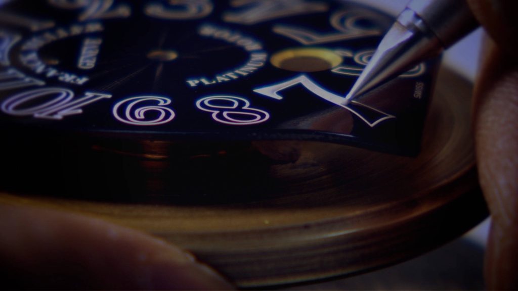 Macro shot of Franck Muller watch dial assembly placing numerals on black platinum face luxury watch Wallpaper