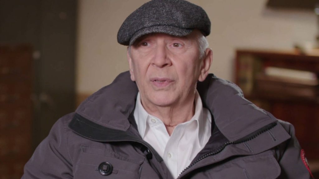 Frank Langella in grey puffer coat and flat cap during professional interview indoor setting wallpaper