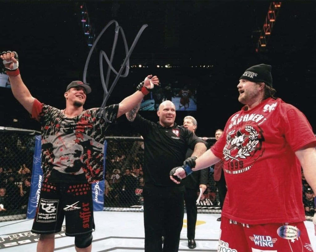 Frank Mir celebrates UFC 130 victory over Roy Nelson with referee Herb Dean in Octagon lights Wallpaper
