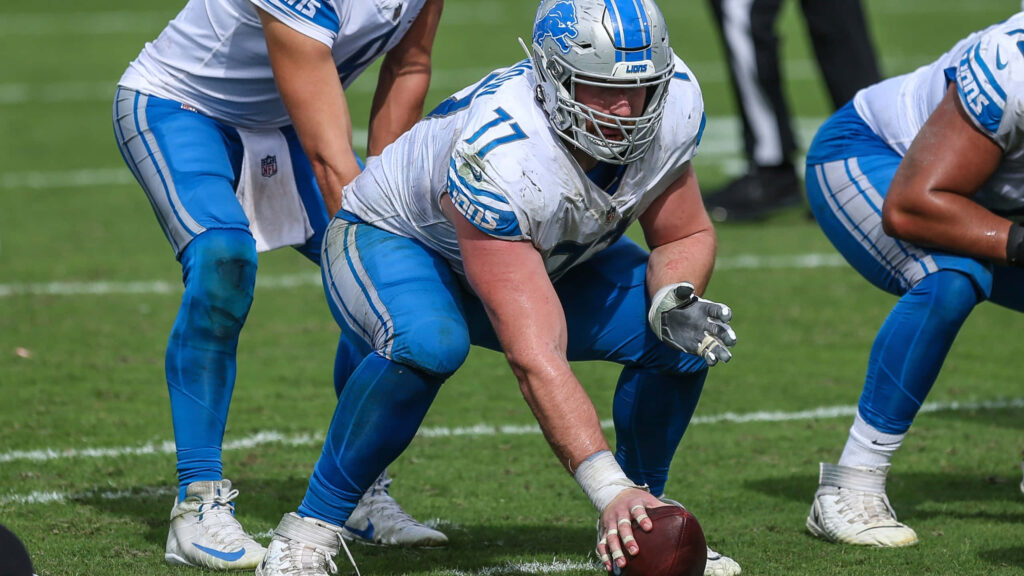 Frank Ragnow Detroit Lions in white and blue uniform ready stance on green turf football field Wallpaper
