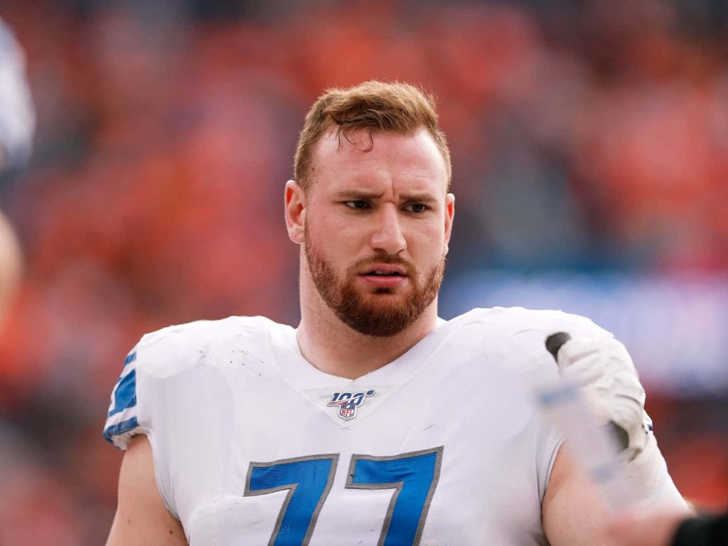Detroit Lions center Frank Ragnow in white jersey number 77 NFL 100 patch stadium background Wallpaper