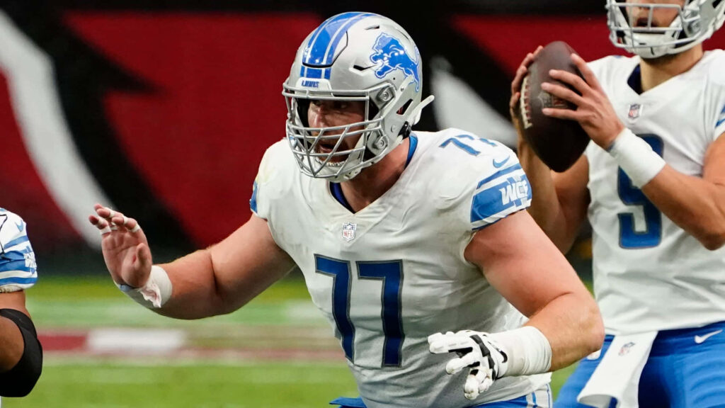 Frank Ragnow and Detroit Lions teammates in blue silver uniforms show teamwork on football field Wallpaper