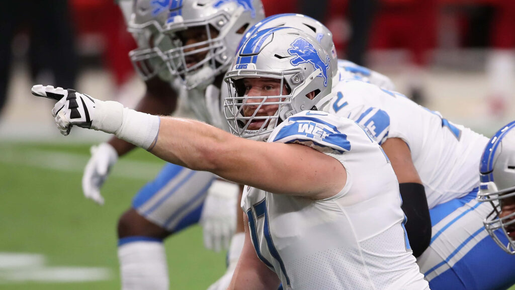 Frank Ragnow leads Detroit Lions offensive line in silver and blue uniform showing focus and energy Wallpaper