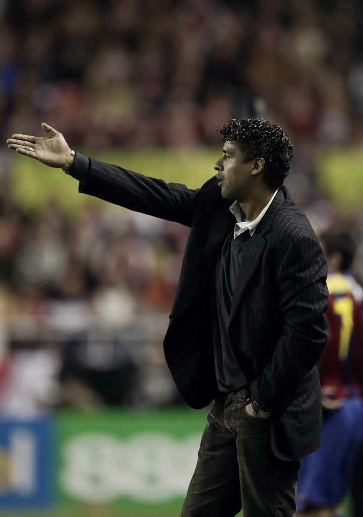Frank Rijkaard in pinstripe blazer coaching football match intense stadium background wallpaper