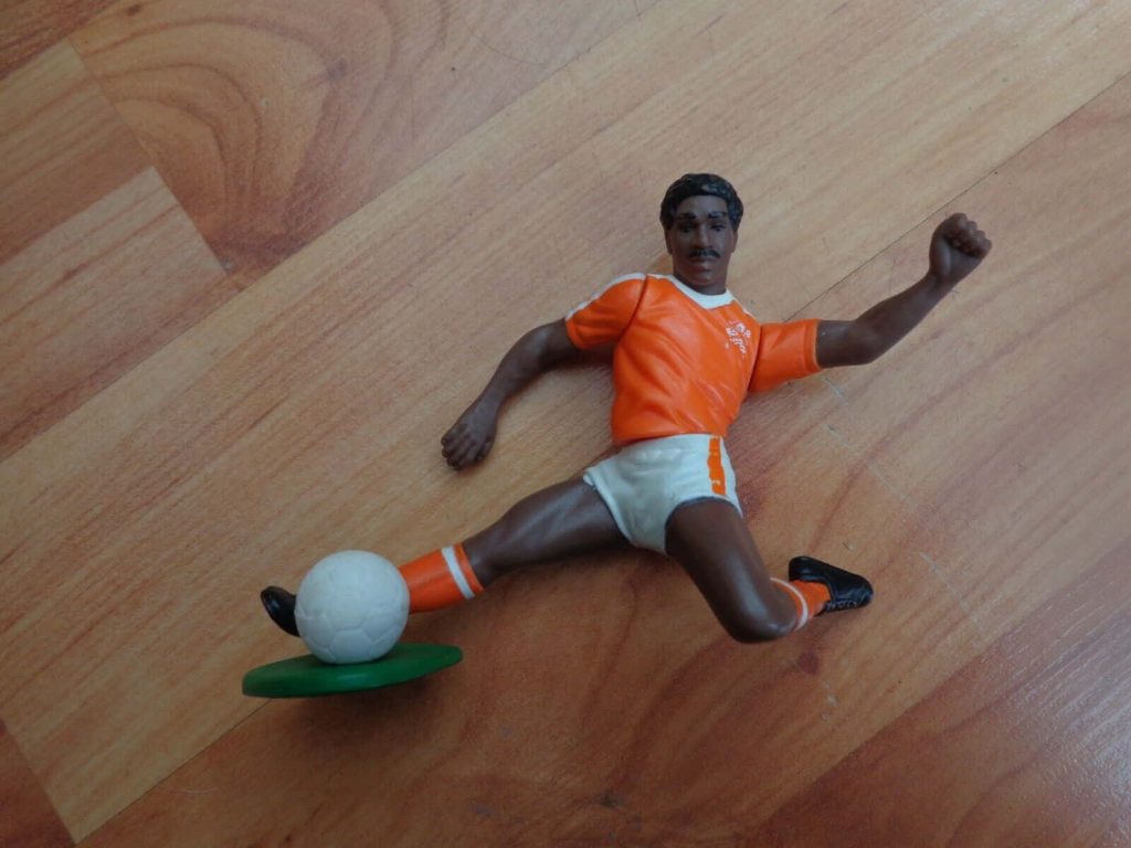 Macro photo of vintage Frank Rijkaard toy in orange Netherlands kit on green stand wooden floor Wallpaper