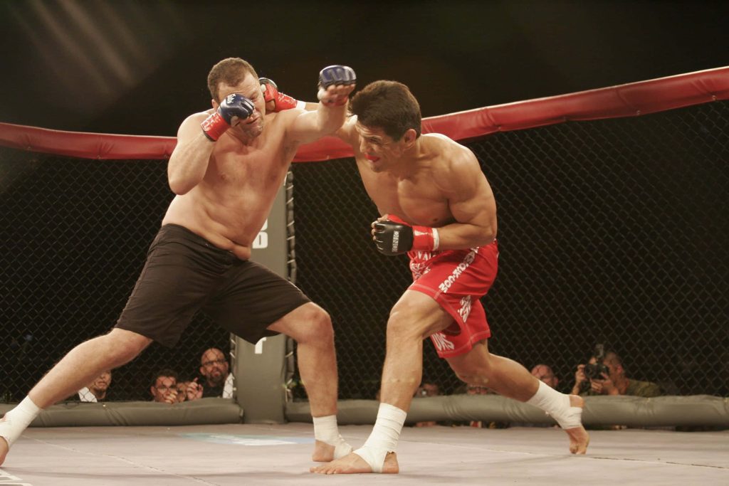 Frank Shamrock delivering a powerful overhand punch to Cesar Gracie in MMA fight action Wallpaper