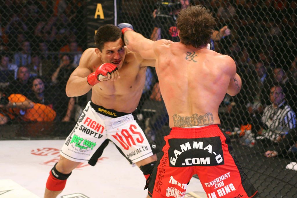 Frank Shamrock and Nick Diaz exchanging strikes intense MMA fight in bright Octagon arena Wallpaper