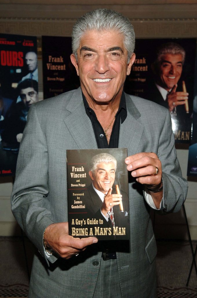 Frank Vincent smiling in grey suit holding A Guy's Guide to Being a Man's Man book wallpaper