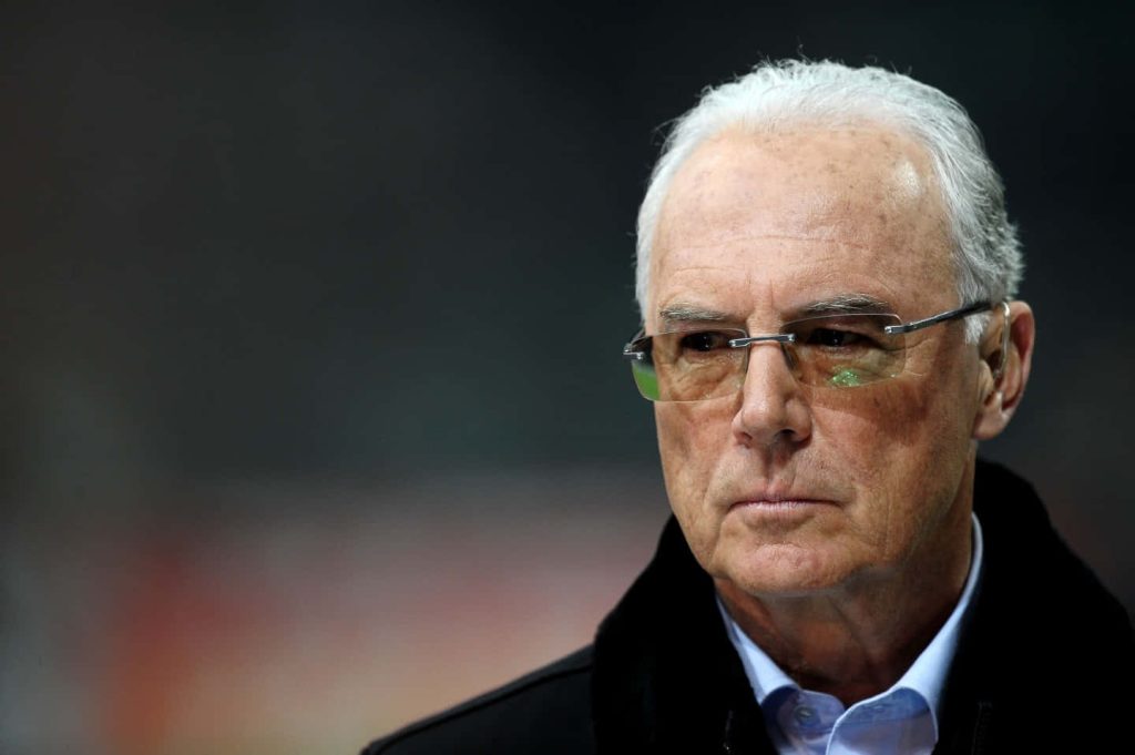 Franz Beckenbauer close-up portrait wearing rimless glasses dark jacket stadium background wallpaper
