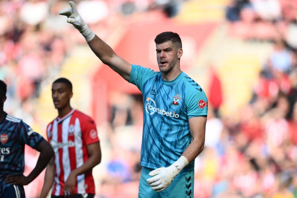 Southampton FC goalkeeper Fraser Forster in teal kit directing defense during match crowd background Wallpaper