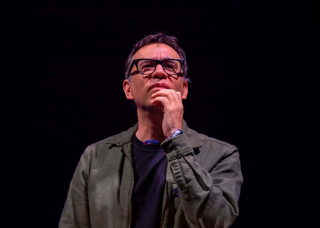 Fred Armisen thoughtful studio portrait wearing glasses green jacket black background lighting Wallpaper